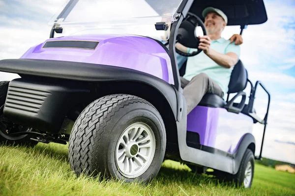 Зрілий чоловік посміхається під час водіння візка для гольфу — стокове фото