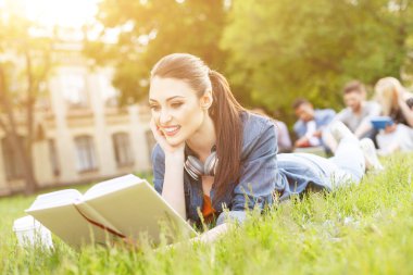 Neşeli genç kadın kampüste okuyor