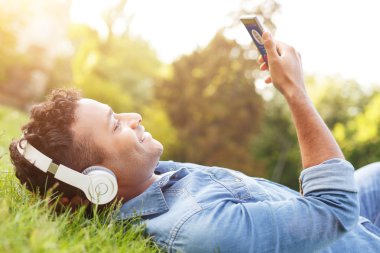 Neşeli Arap adam çimenlerin üzerinde rahatlatıcı