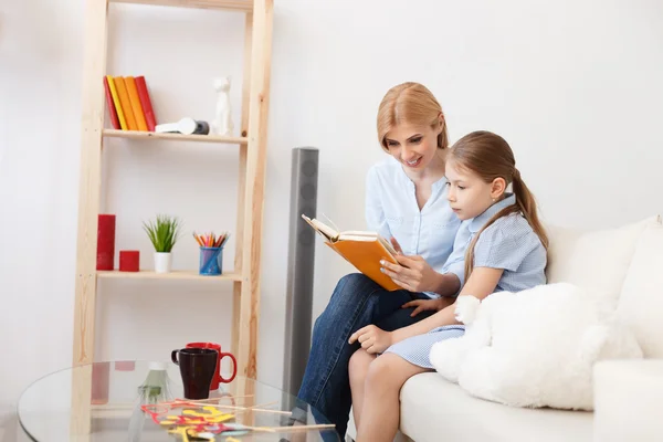 Mãe e filha lendo livro em casa — Fotografia de Stock