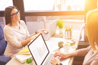 Akıllı iki iş kadını iş için dizüstü bilgisayar kullanıyor