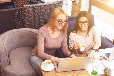 Kafeteryada dizüstü bilgisayar kullanan akıllı kadın iş arkadaşları