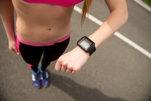 Szczupła kobieta runner przy użyciu inteligentny zegarek — Zdjęcie stockowe