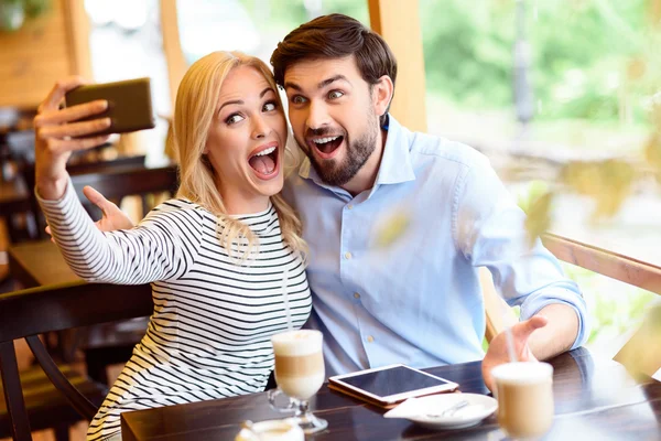 Cute loving couple photographing themselves in cafeteria — Stock Photo, Image