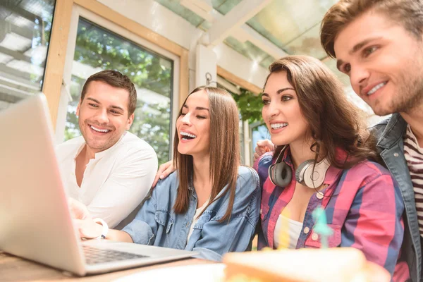 Fyra vänner i kafé med laptop — Stockfoto