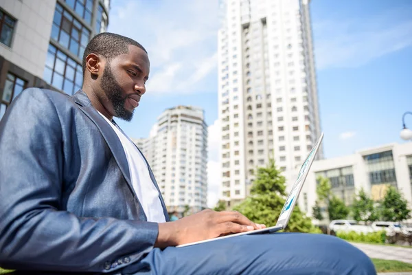 Nadenkend jongeman laptop gebruiken in de stad — Stockfoto