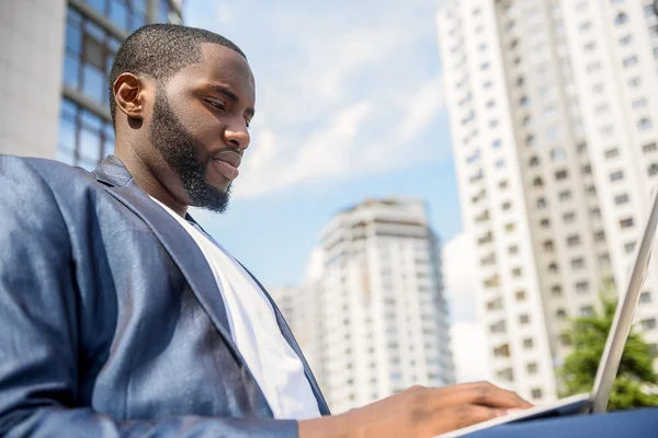 Серйозні африканських бізнесмен працює над ноутбук на відкритому повітрі — стокове фото