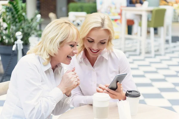 Alegre cerca de las mujeres utilizando el teléfono inteligente con alegría — Foto de Stock