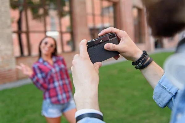 Guy photographing his girlfriend outdoors — Stock Photo, Image