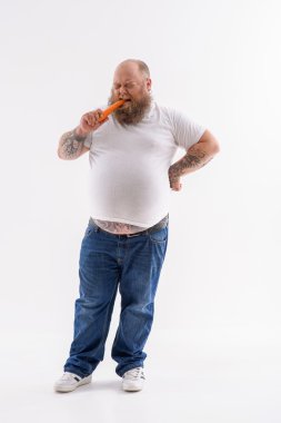 Şişman adam tiksinti ile sebze ısırma