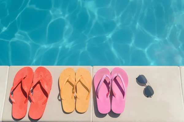 Zapatillas y vasos de colores cerca del agua — Foto de Stock