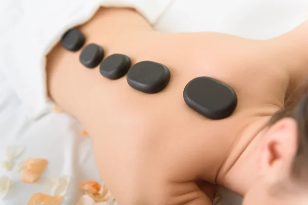 Ung tjej får stenar massage på spa — Stockfoto