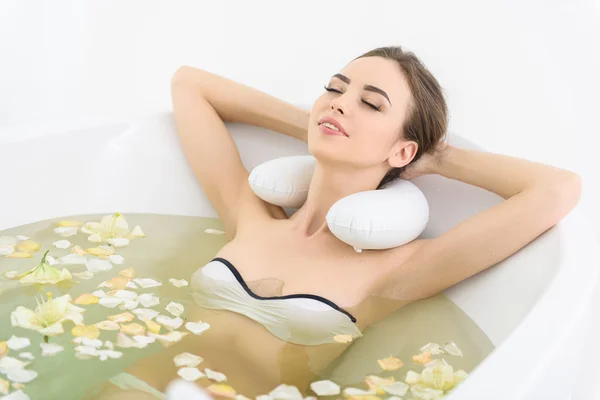 Mujer joven y bonita disfrutando del agua con pétalos — Foto de Stock