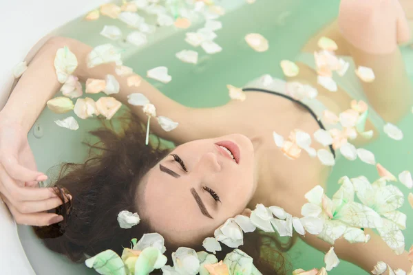 Menina atraente mimos na água com flores — Fotografia de Stock