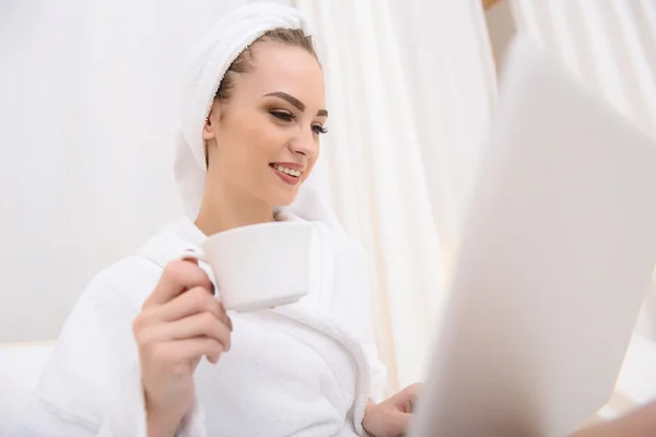 Mujer joven feliz usando la computadora en el salón de belleza — Foto de Stock