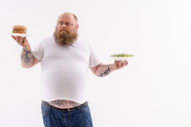 Şişman adam sandviç ve salata arasında seçim