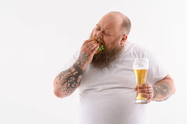 Fat guy biting unhealthy sandwich — Stock Photo, Image