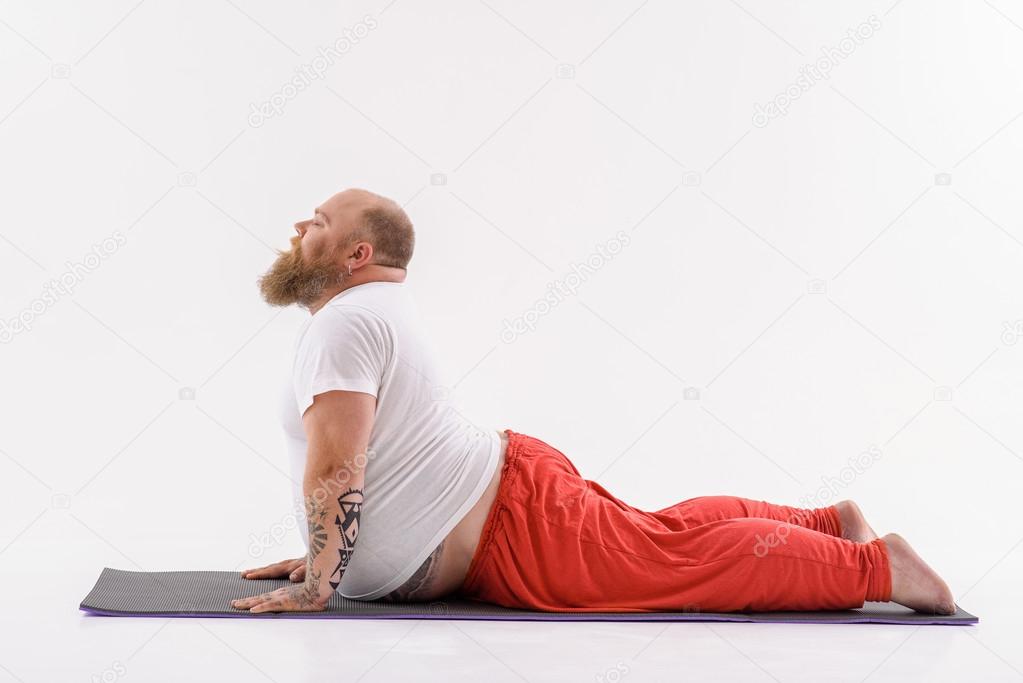 Relaxed fat man doing yoga Stock Photo by ©iakovenko123 119820450