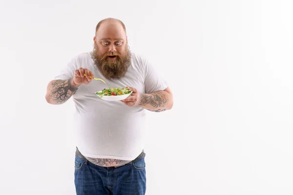 Happy fat guy eats vegetables — Stock Photo, Image