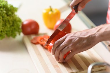 Young man cutting pepper on board
