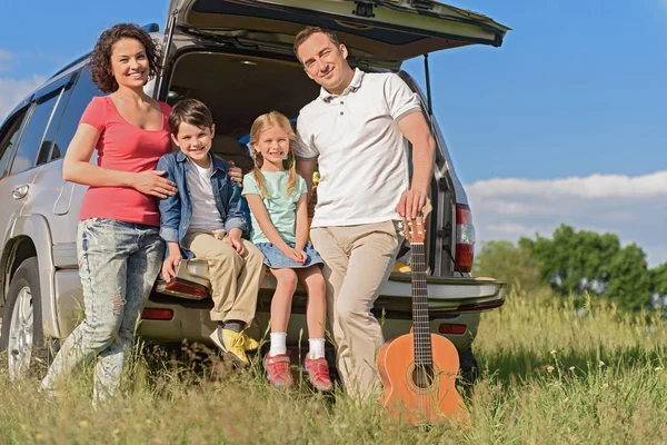 Lachende gelukkige familie en hun auto — Stockfoto