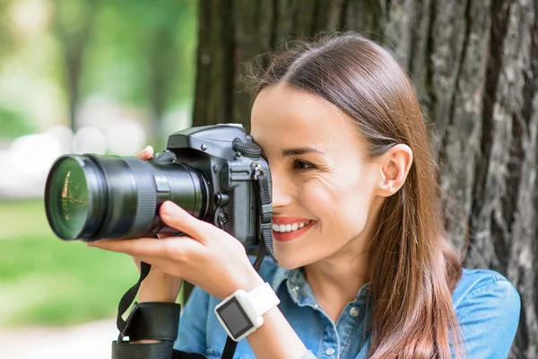 Glad ung kvinna fotograferar i parken — Stockfoto