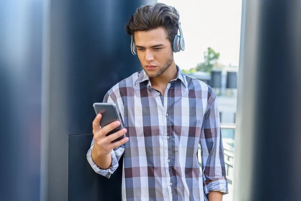 Serious guy using phone with earphones — Stock Photo, Image