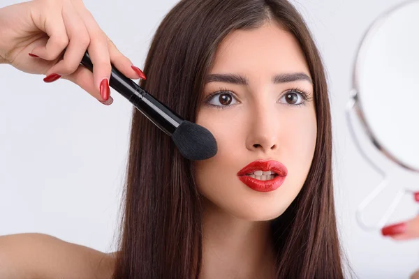 Aantrekkelijke jonge vrouw die make-up doet — Stockfoto