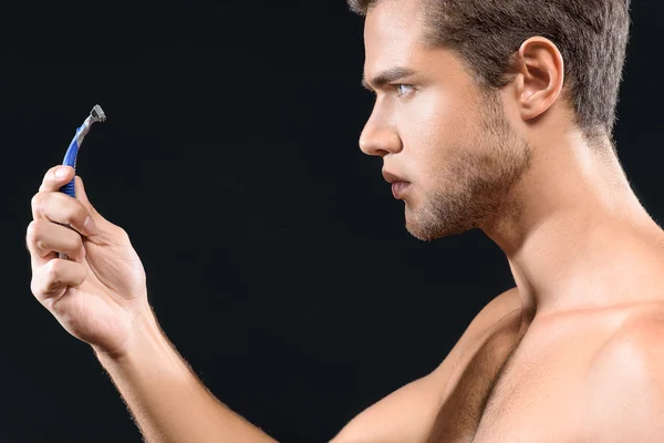 Düşünceli erkek tıraş makinesi bakıyor — Stok fotoğraf