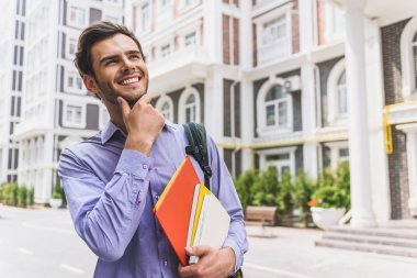 Şehirde kitaplarla neşeli erkek öğrenci