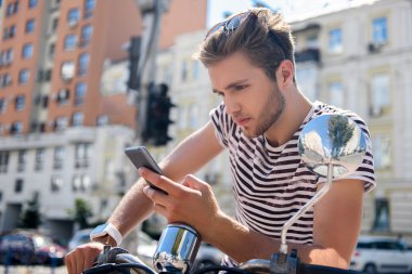 Düşünceli adam scooter üzerinde telefon ile