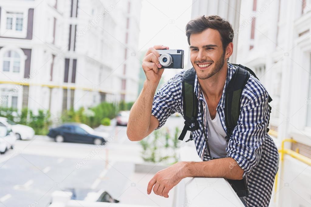 Happy male tourist photographing urban architecture