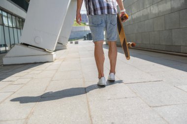 Neşeli erkek kaykaycı sahip açık havada yürümek