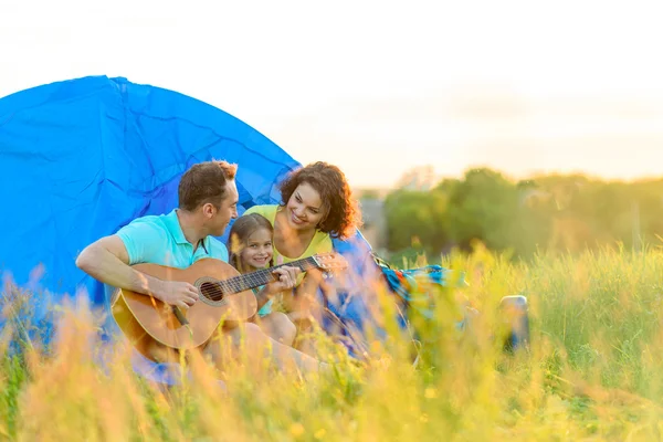Lycklig familj sitter nära tält — Stockfoto