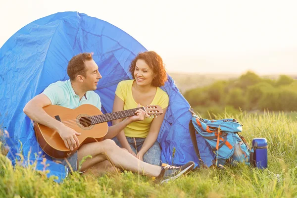 Feliz pareja sentada cerca de tienda con guitarra — Foto de Stock