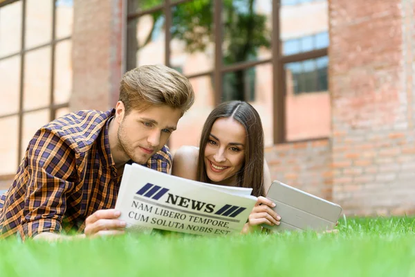 Pareja alegre relajándose con papel sobre hierba — Foto de Stock