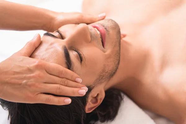 Hombre feliz recibiendo tratamiento facial en el centro de masaje —  Fotos de Stock