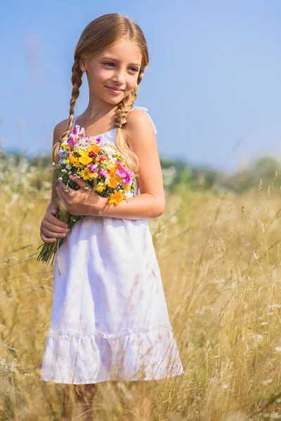 Мила дівчинка з квітами на лузі — стокове фото