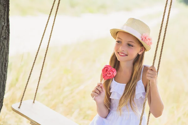 Menina feliz balançando com doces — Fotografia de Stock