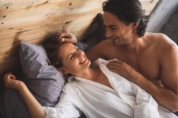 Joven somnolienta mujer mirando a su novio en una cama — Foto de Stock