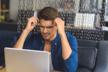 düşünmeye çalışıyorum bir dizüstü bilgisayar önünde genç serbest meslek