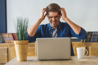 genç erkek freelancer baş ağrısı yüzünden çalışamaz