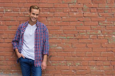 Tuğla duvara yakın duran yakışıklı adam