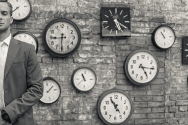 Erkek takım elbise ayakta duvar saatleri ile yakın