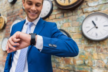 Erkek takım elbise ayakta duvar saatleri ile yakın