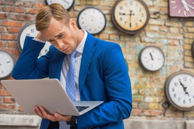 Erkek takım elbise ayakta duvar saatleri ile yakın