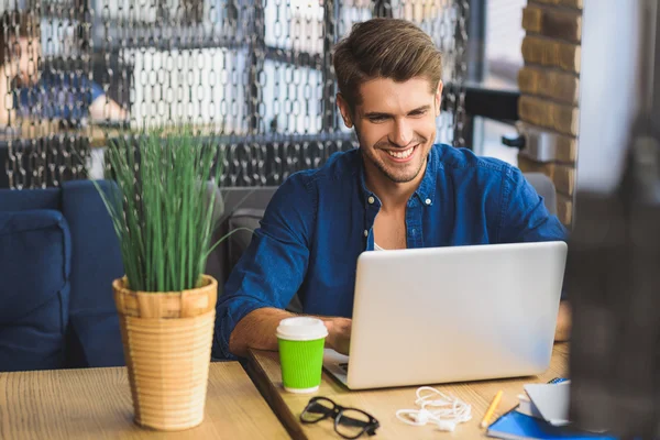 Junge Freiberuflerin vor einem Laptop, der zähneknirschend lächelt — Stockfoto