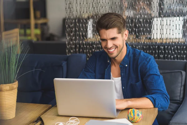 Jovem freelancer na frente de um laptop sorrindo com os dentes — Fotografia de Stock