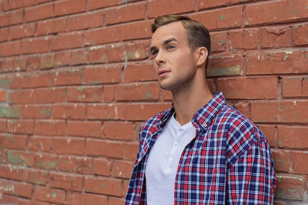 Handsome guy standing near brick wall — Stock Photo, Image