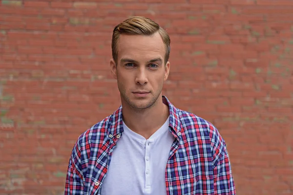 Tipo guapo de pie cerca de la pared de ladrillo — Foto de Stock